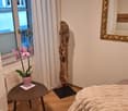 wooden floor, side table, white walls, window, radiator, mirror, table with flower