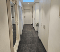 empty corridor, tile flooring, large mirror, white wall, small light above corridor, closed door