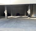 underground parking lot, concrete walls, two cars parked, concrete floor
