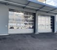 Industrial building with large garage doors, metal siding, and a paved parking area.
