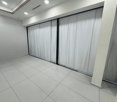 empty room with white tiled floor, white walls, sliding glass doors, and white curtains