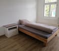Single bed, nightstand, window, gray bedspread
