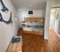 A room with wooden floor, white walls, bunk bed, whale wall art, wooden desk with books, and a lamp