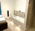 modern bathroom with bathtub, two sinks, toilet, and shower