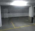 Empty parking space with yellow lines, white walls, and a white door.