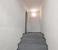 Staircase with gray tiles, white walls, ceiling light