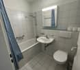 Bathroom with bathtub, sink, toilet, and mirror mounted above sink