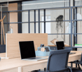 A wooden desk with 2 laptops, 2 chairs, storage box, and a shelf with books