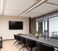 Modern meeting room with large table, flat screen TV, glasses and bottles, chairs, black decor