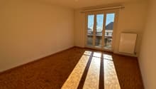 Empty room, parquet floor, white walls, sliding glass door to a balcony