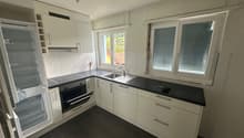 modern kitchen with white cabinets, black countertops, stainless steel appliances, double sink, and a window with blinds