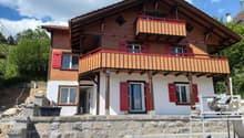2 story house, wooden exterior, red shutters, balconies, stone foundation