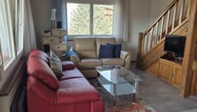 large couch, coffee table, TV, small table with speaker, window, stairs