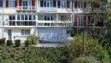 3 story apartment building, white exterior, red shutters, balconies, garage, garden, river view