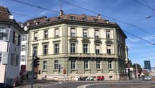 corner building, multiple stories, green color, balcony, windows, traffic lights, people, motorcycles