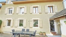 2 story house, beige exterior, white shutters, glass table, chairs, potted plants, entrance
