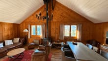 fireplace, wooden walls, chandelier, dining table, chairs, couch, rug, coffee table