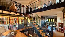 High ceiling, wooden floor, spiral staircase, study with bookshelves, living room with couch, musical instrument, balcony with drum set