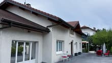 Detached house, white exterior, tiled roof, double glass doors, small table with chairs, outdoor seating area, paved driveway