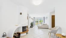 white walls, tiled floor, fireplace, couch, armchair, plant, table, lamp