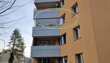 3-story apartment building with beige paint, balcony, glass windows, outdoor plant boxes