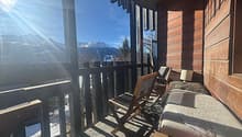wooden balcony with railings, wooden chairs, lamp, wooden bench, view of mountains