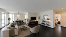 / a large living room with black floors and white furniture and a black table and chairs