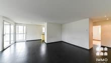 / an empty living room with black floors and a large sliding door