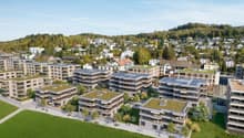 Multiple residential buildings with green roofs, solar panels, landscaped gardens, walking paths, surrounding trees and grass, townscape in the background