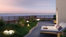 Outdoor lounge area with couch, decorative lamps, grass, and sea view.