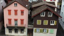 multistory building, brown roof, pink building, windows with shutters, metal railing on balcony