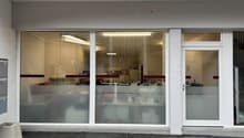 Commercial building with glass facade, white walls, two glass doors, and a small concrete planter.