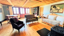 wooden floor, wooden beams, fireplace, sofa, couch, chair, table, bookshelf, painting