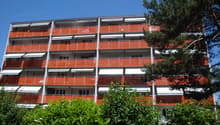multi-story building, multiple balconies with orange railings, white awnings
