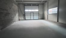 Empty room, industrial style, brick wall, white ceiling, overhead lighting, white door, fire extinguisher, window, wide open entrance