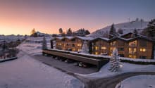 Modern building with wooden facade, large windows, covered parking, snow covered landscape