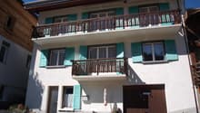 white house, 3 floors, turquoise shutters, brown garage door, balcony on each floor