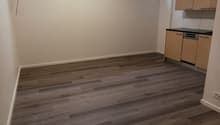 empty room, wooden floor, white walls, kitchen area with cabinets and dishwasher