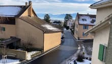 Houses on a street, snow on the ground, mountains in the distance