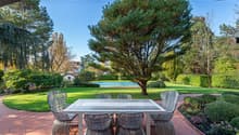 outdoor dining table with chairs, swimming pool, lawn, garden, house, trees