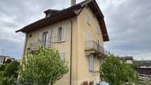 2 story house, beige paint, several windows, balcony on second floor, small front garden