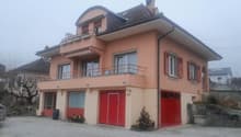2 story house, red garage doors, balcony, gravel driveway