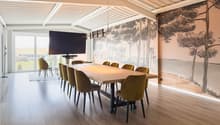 long dining table, 12 chairs, large screen on wall, wooden floor, large windows