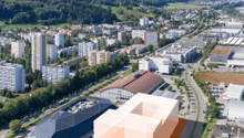 The image shows an aerial view of an industrial site located in the Limmattal area of Spreitenbach AG. The site consists of several large industrial buildings and warehouses, some of which are highlighted in orange. The surrounding area appears to be a mi