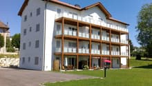 white exterior, balconies, red roof, grassy area, outdoor seating