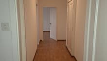 wooden floor, white walls, entrance, doors to rooms, bright lighting