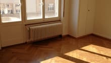 empty room, wooden parquet flooring, large windows, wooden door, white radiator, wooden built-in closets, power outlet