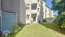 3-story apartment building with balconies, garage, and a well-maintained garden area in the front.