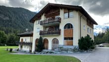 two story building, balconies, large grassy field, trees, mountains
