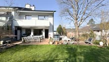 2 story house, white exterior, large windows, balcony, outdoor dining area, garden, trees, lawn